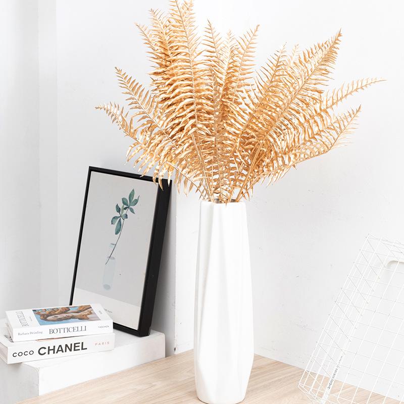 Trang trí đám cưới giả màu vàng: lá eucalyptus, hoa giả, cành giả, chi tiết vàng cho trang trí lối đi.